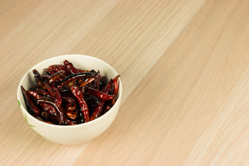 Roested dried red chili pepper in cup on wooden table