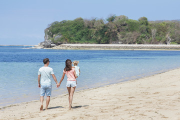 young mother holding hands with her husband while carrying her l