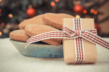 Vintage photo, Wrapped gift, gingerbreads and christmas tree with lights in background