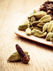 cardamom pods and cloves on wooden spoon