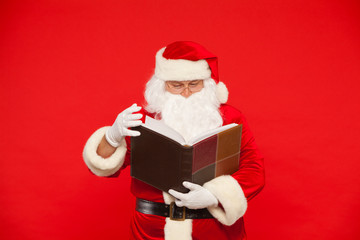 Santa Claus reads old book, on a red background. Christmas