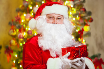 Santa Claus with giftbox on background of sparkling firtree