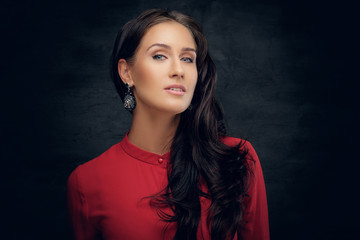Portrait of a brunette woman with waving hair in a red shirt.