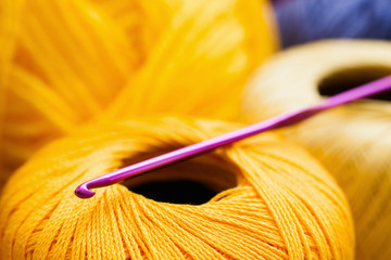 Yellow thread with crochet close-up, handiwork background. Several balls of xanthous yarn with...