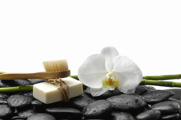 Fototapeta na wymiar White orchid blossom with black stones ,grove,soap on wet background