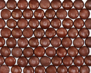 Dark brown dragee in chocolate covered. Whole background.