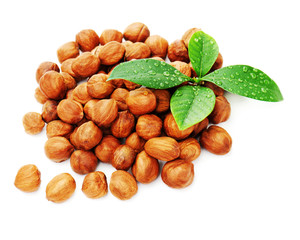 Heap of fresh shelled hazelnuts with green leaves isolated on white background. Closeup.