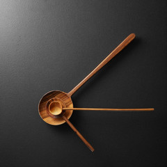 Top view of black alarm clock with wooden spoons