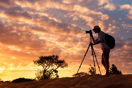 Female photographer taking picture in a beautiful nature setting. Adventure and travel concept. 