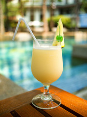 Pina Colada cocktail on a table on tropical island. Palm trees o