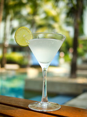 Martini cocktail on a table on tropical island. Palm trees on ba