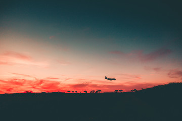 Beautiful sunset with a Silhouette of an Airplane approaching at the Airport. 