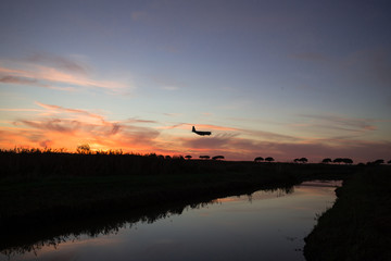 Aereo passeggeri in avvicinamento alla pista di atterraggio durante un tramonto.