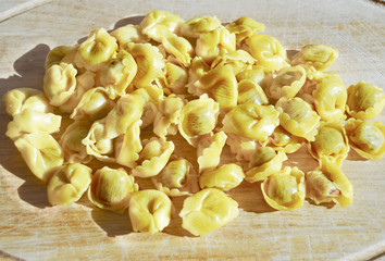 raw tortellini on a wooden board