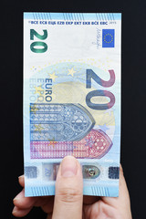 Twenty Euro on hand and gold coins for background 