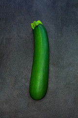 Fresh green zucchini isolated on dark gray slate stone backgroun