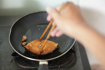 fried mackerel in black pan, little blur, slow speed, swallow deep of field