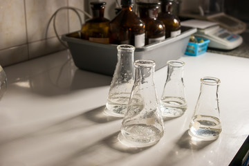 Flasks with transparent liquid. Beakers on table. Compare samples of water. Experiments show amazing results.