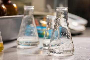 Beaker with transparent liquid. Flask on blurred background. Sample of water for analysis. Make a contribution to science.