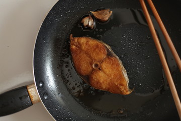fried mackerel in black pan, little blur, slow speed, swallow deep of field
