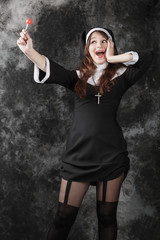 young sexy stockings nun holding a red candy on a dark background. girl looking for a sweet and...