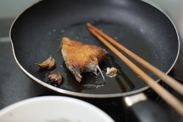 fried mackerel in black pan, little blur, slow speed, swallow deep of field