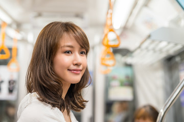 Happy beautiful japanese girl smiling inside subway train