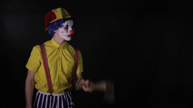 Scary clown juggling axe in a dark room. Frightening jester, clown, buffoon. hd.