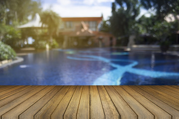 Wooden board empty table against of blurred swimming pool background. Perspective brown wood over swiming pool can be used for display or present your products.Mock up your products