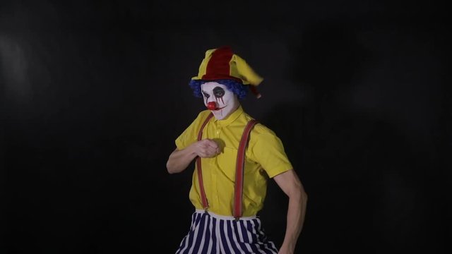 Scary clown with a chainsaw in the dark. Clown murderer threatening you. HD.