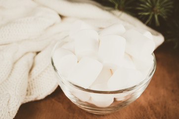 Cozy winter background. Marshmallow and Warm Knitted Plaid on Wooden Background.