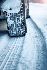 Obraz premium Closeup of car tires in winter on the road covered with snow