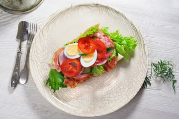 sub sandwich home, bacon, sausage, egg and greens on a baguette,  plate, top view, still life