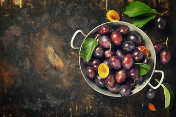 Plums in a bowl on a rural background