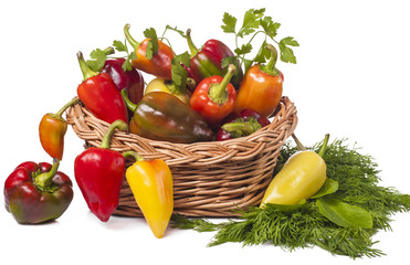 on white background colorful peppers in basket and salad greens