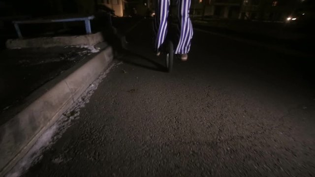 Sad scary clown riding on unicycles in a dark street. HD.
