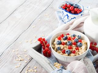 Wooden background with bowl of porridge and berries
