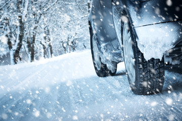Car tires on winter road covered with snow. Vehicle on snowy alley in the morning at snowfall