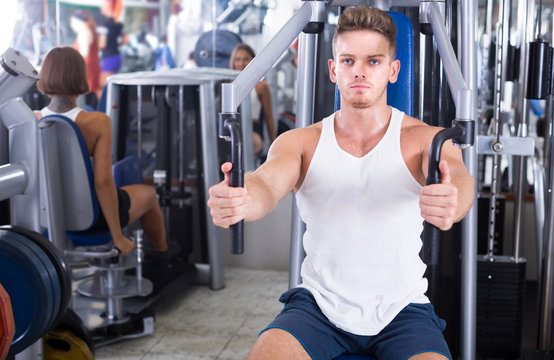 Young man training upper body using fly machine