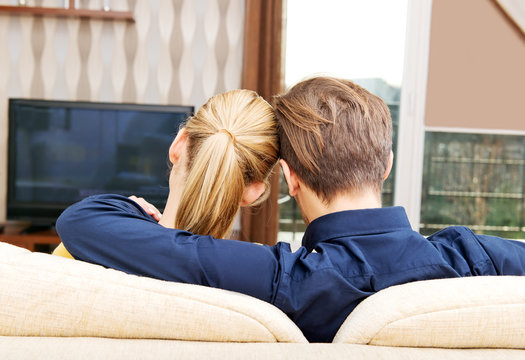 Back view of a couple watching tv at home