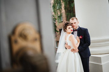 Fototapeta premium Beautiful couple, bride and groom looking at the camera on a background castle gate
