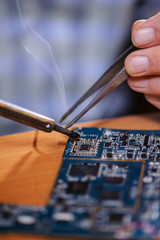Male hands with soldering iron and tweezers
