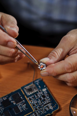 Electronic engineer holding chip with tweezers