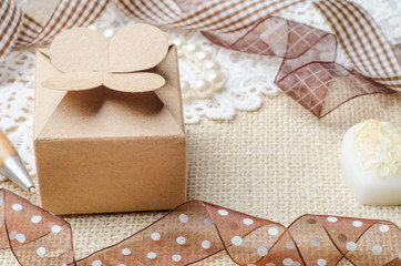 Vintage brown paper gift box with ribbon on burlap sack backgrou