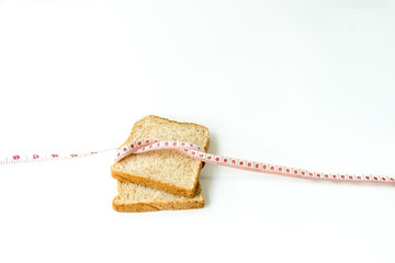 Healthy lifestyle fitness weight control concept. Closeup whole wheat bread with measuring tape