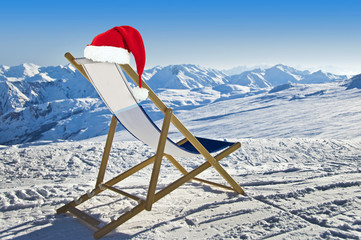 Santa hat on a deckchair on the side of a ski slope, snowy mountain landscape