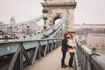 Christmas in old town. Young cheerful caucasian couple in warm cozy clothes walking in city centre.