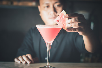 Barman is decorating cocktail with watermelon no face focus select.