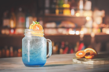 Blue cocktail drink on the bar counter and light bokeh.
