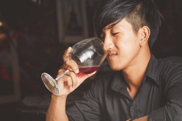 Asian man drinking red wine.